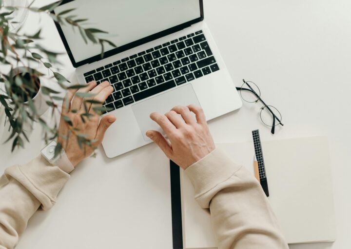 Free An overhead view of a person working on a laptop in a minimalist home office setting. Stock Photo